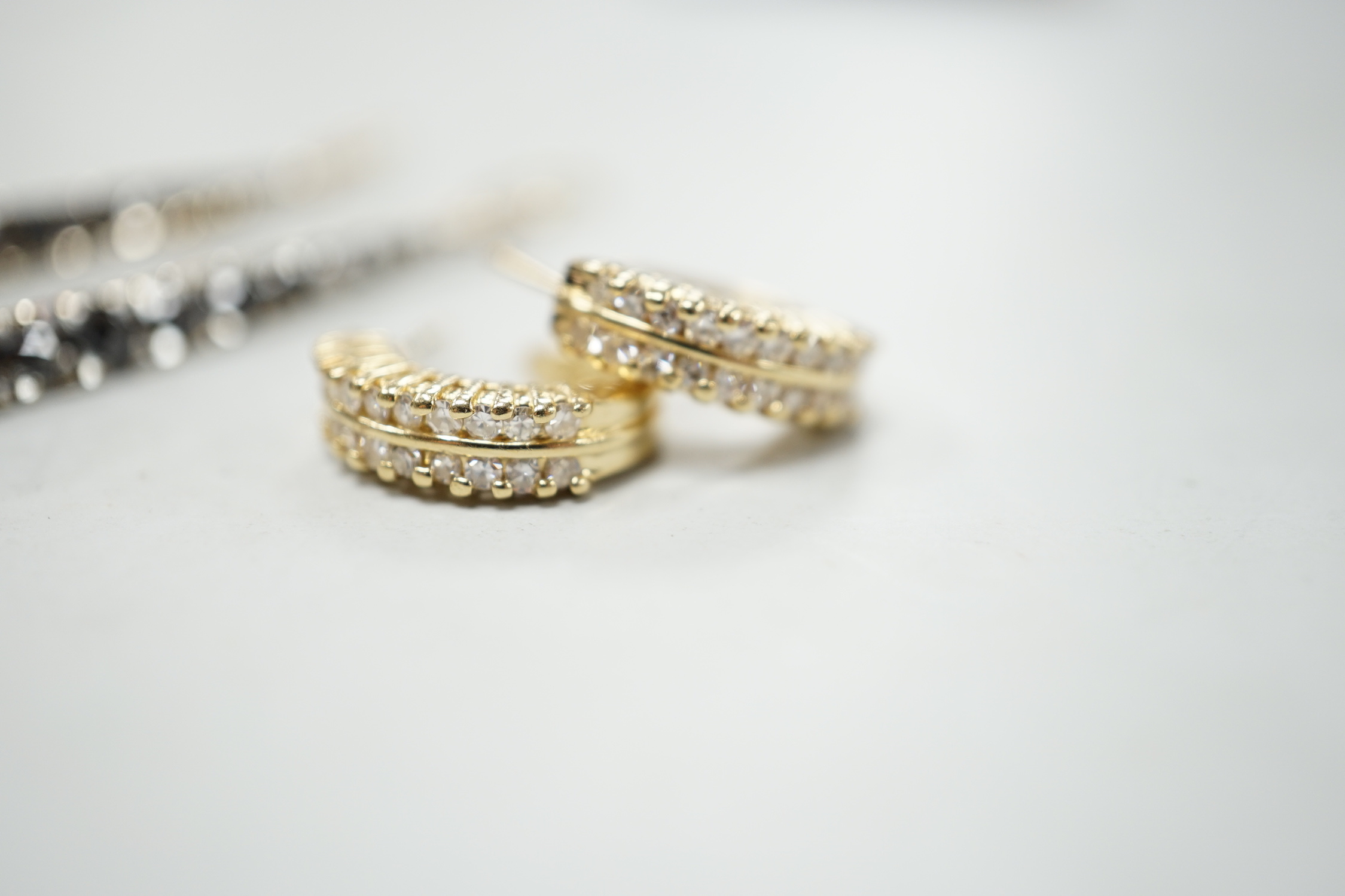 A modern pair of 14k yellow metal and two row diamond chip set half hoop earrings, 14mm, gross weight 4.6 grams, together with a modern pair of 18ct gold and two colour diamond set line earrings, 47mm, gross weight 5.3 g